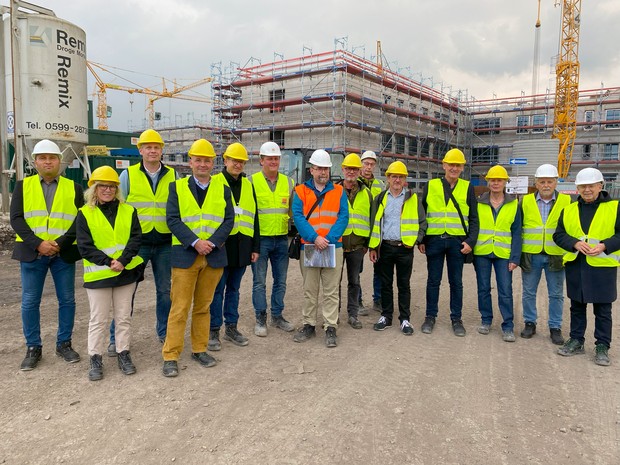 Eine Gruppe von Menschen mit Bauhelmen und Leucht-Schutzwesten steht auf einer Baustelle vor einem großen eingerüsteten Gebäude. (Bild: LWL/SchuFi) Eine Gruppe von Menschen mit Bauhelmen und Leucht-Schutzwesten steht auf einer Baustelle vor einem großen eingerüsteten Gebäude. (Bild: LWL/SchuFi)