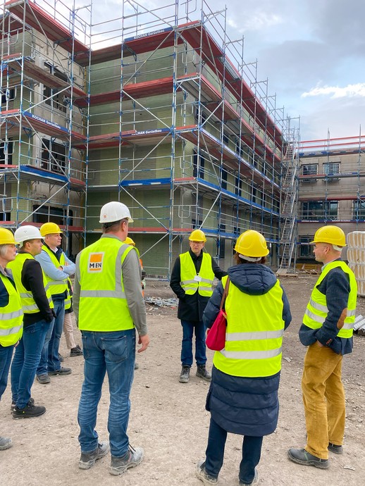 Eine Gruppe von Menschen steht in Bau-Schutzkleidung vor einem dreigeschossigen, eingerüsteten Gebäude, einer erklärt etwas.(Bild: LWL/Schufi) (vergrößerte Bildansicht wird geöffnet)