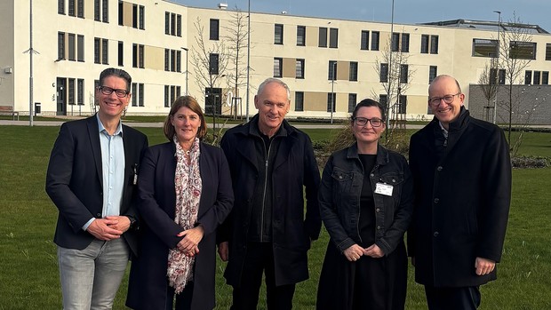 Zwei Frauen und drrei Männer stehen lächelnd vpr einem großen Gebäude mit vergitterten Fenstern. (Bild: LWL)