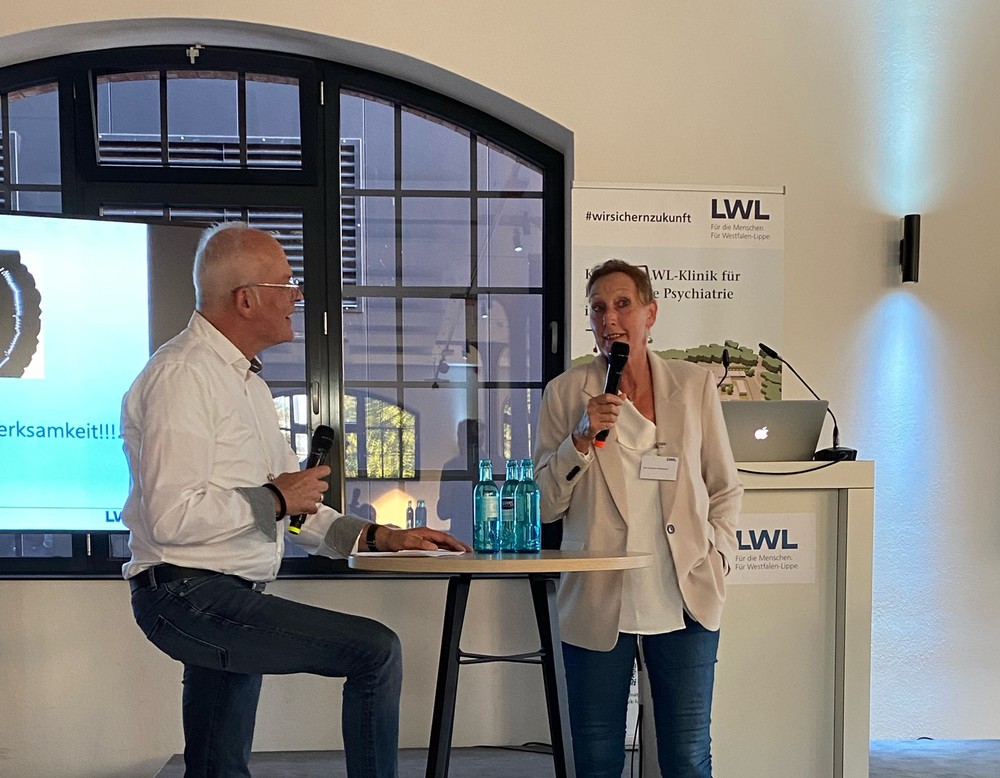 Ein Moderator im Gesspräch mit einer Referentin am Stehtisch (Bild: LWL/SchuFi)