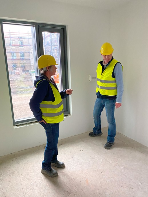 Zwei Menschen in Bau-Schutzkleidung betrachten einen Raum mit einem teilvergitterten Fenster. (Bild: LWL/Schufi) (vergrößerte Bildansicht wird geöffnet)